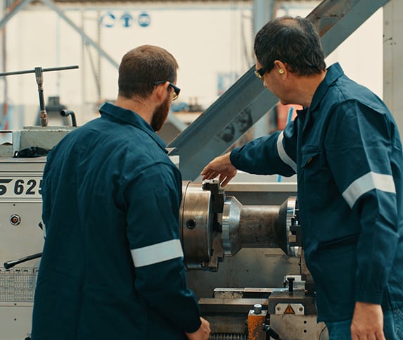 two male manufacturing professionals train together on a machine