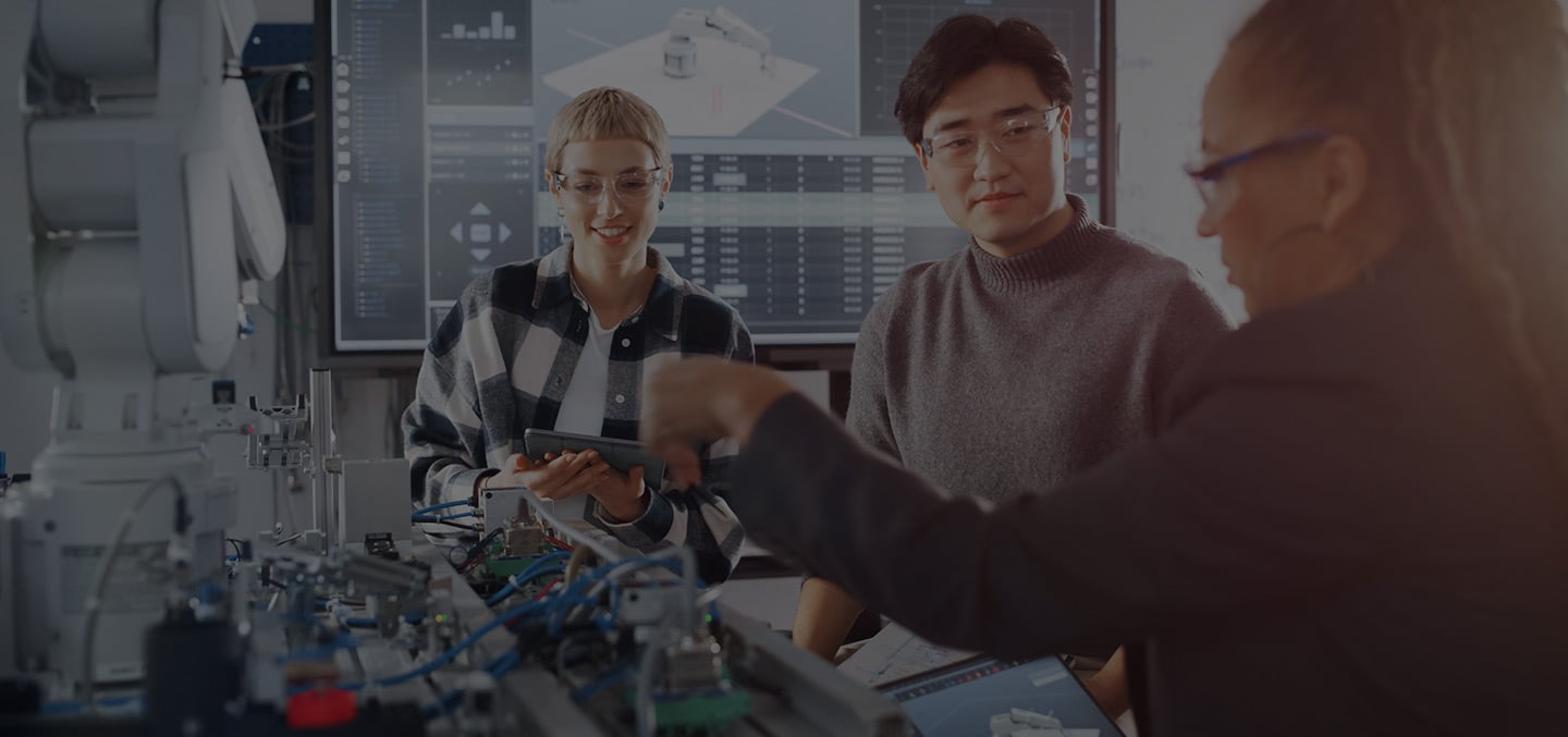 Two females and one male manufacturing workforce professionals use a robot during manufacturing fundamental training.