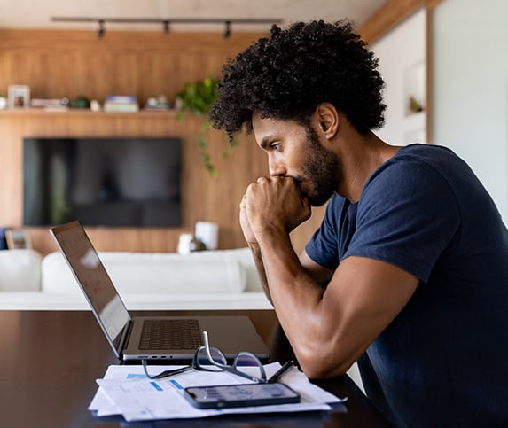 Young black manufacturing professional sits in front of a laptop computer in his home taking online manufacturing fundamental classes from Tooling U-SME.