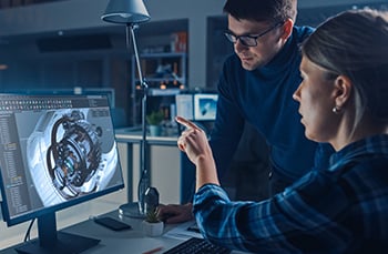 male and female engineers working on a manufacturing solution in front of a computer