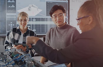 Two females and one male manufacturing workforce professionals use a robot during manufacturing fundamental training